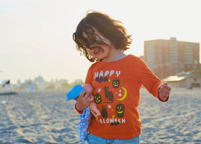 Young girl is playing on the beach on a warm day in a halloween shirt