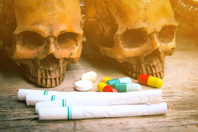 Close-up of pills and cigarettes with human skull on table