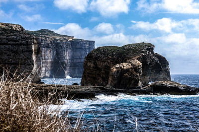 Rock formations by sea against sky