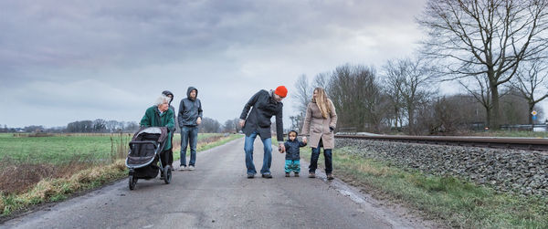 Full length of family walking on road against sky