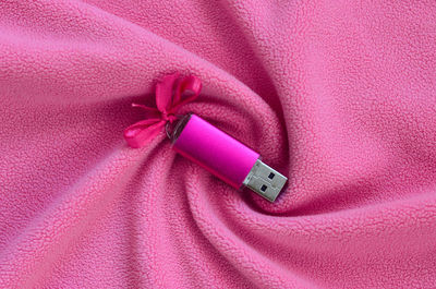 Directly above shot of usb stick with ribbon on pink textile