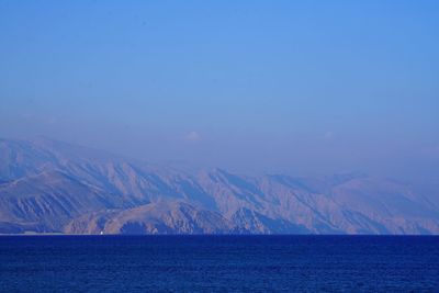 Scenic view of sea and mountains against blue sky