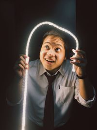 Portrait of smiling man standing against black background