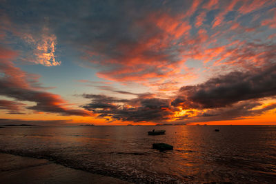 Scenic view of sea against dramatic sky during sunset