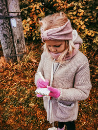 Girl wearing hat while standing and writing down geocahing during autumn