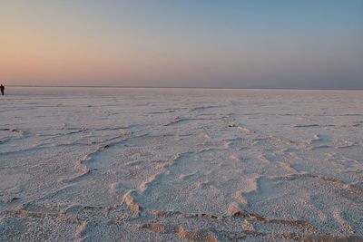 Scenic view of salt flat against clear sky during sunset