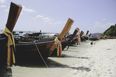 Fishing boats moored on beach against sky
