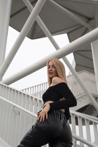 Young woman standing on railing against ceiling