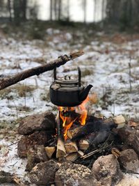 Kettle hanging over campfire in forest during winter