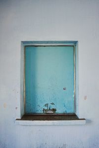 Closed blue window on white wall