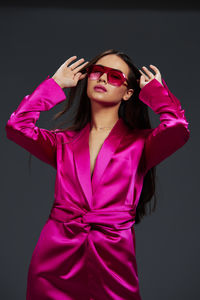 Portrait of young woman wearing sunglasses against yellow wall