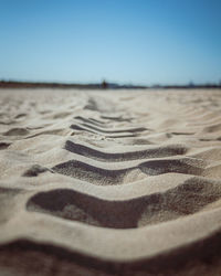 Surface level of sand against clear sky