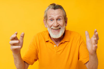 Portrait of young man gesturing against yellow background