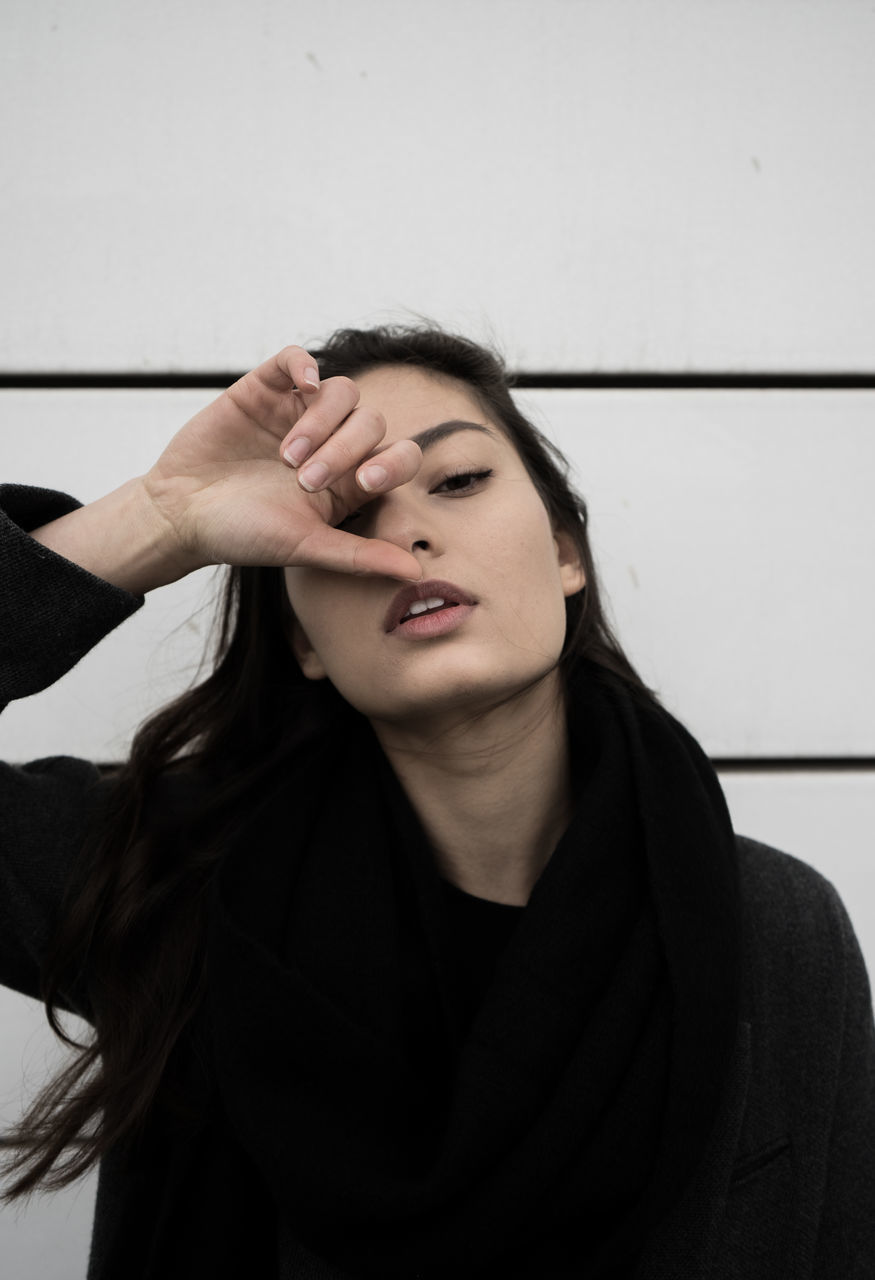 CLOSE-UP OF BEAUTIFUL YOUNG WOMAN STANDING BY WALL