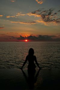 Silhouette man on beach against sky during sunset