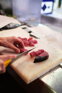 Young woman cuts up a red fish in her fishmonger's