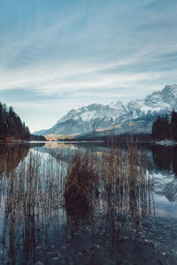 Scenic view of lake by snowcapped mountains against sky