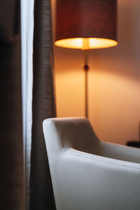 Close-up of illuminated lamp above chair in room
