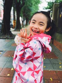 Portrait of cute girl standing on footpath