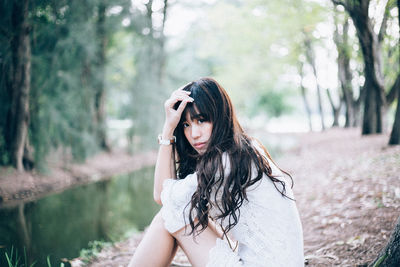 Portrait of young woman sitting at forest