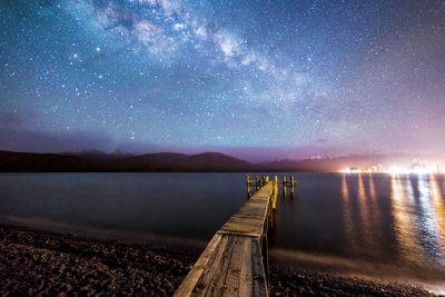 Scenic view of jetty in calm sea against sky at night