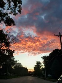 Low angle view of silhouette trees against dramatic sky