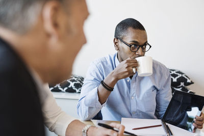 Businessman drinking coffee during meeting at office
