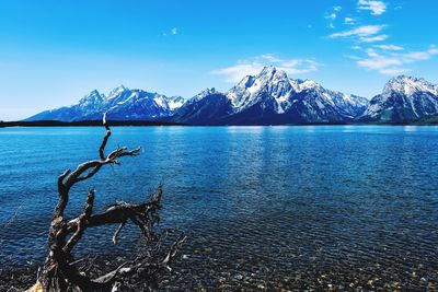 Scenic view of lake and mountains against blue sky