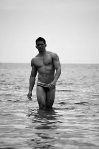 Full length of shirtless man standing in sea