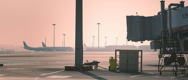 Airplane at airport against sky during sunset