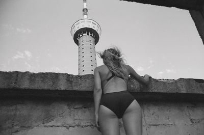 Woman standing by umbrella against sky