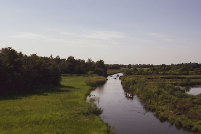 Scenic view of landscape an small river against sky