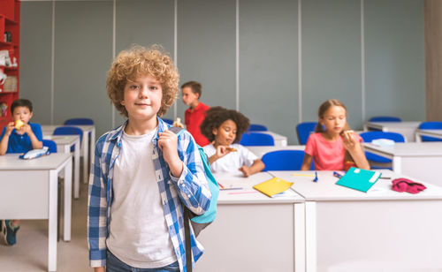 Portrait of cute boy standing in classroom