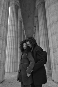 Couple romancing while standing against architectural columns