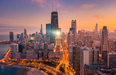 Illuminated buildings in city against sky