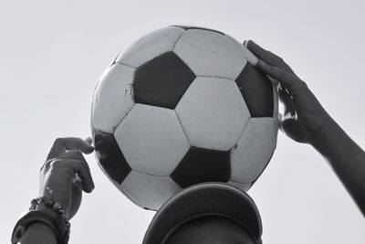 Low angle view of hand holding ball against clear sky