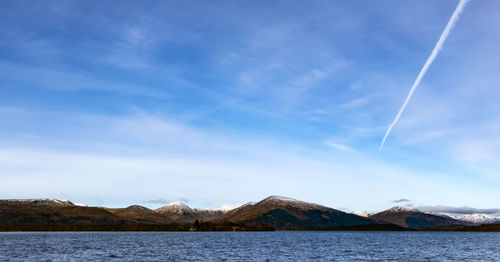 Scenic view of lake and mountains against blue sky