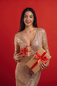 Portrait of young woman standing against yellow background
