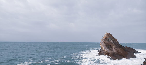 Rock formation in sea against sky