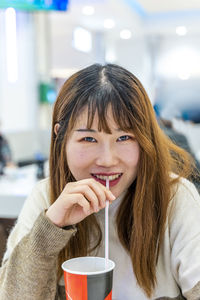 Portrait of chinese young adult drinking a soft drink sitting in a shop after shopping