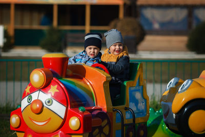 Children's rest in the amusement park. two boys ride a children's colored locomotive by rail. 