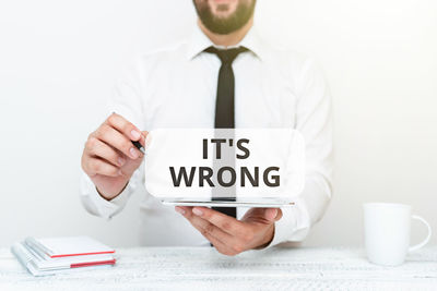 Midsection of man holding paper with text