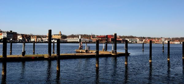 Pier over river against clear blue sky