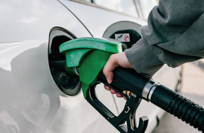 Hand refilling car with fuel at gas station.