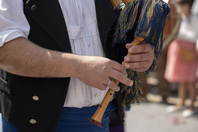 Midsection of man playing bagpipe on street