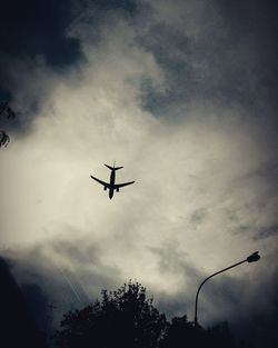 Low angle view of silhouette airplane flying in sky