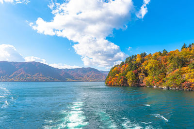 Scenic view of sea by mountains against sky