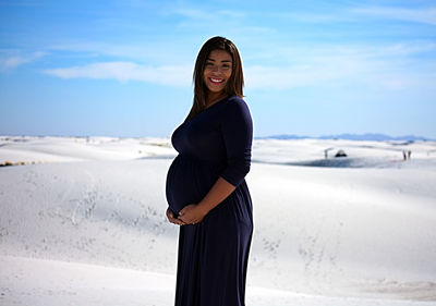 Portrait of smiling young woman standing on beach against sky