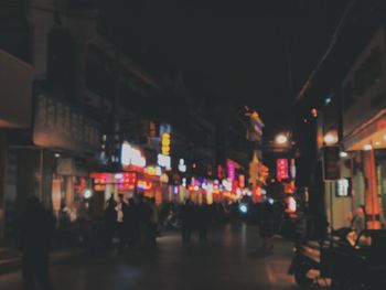 People walking on illuminated street at night