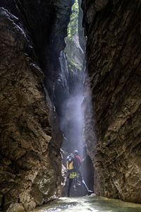 View from behind a canyoner in a beautiful canyon with a beam of light and fog